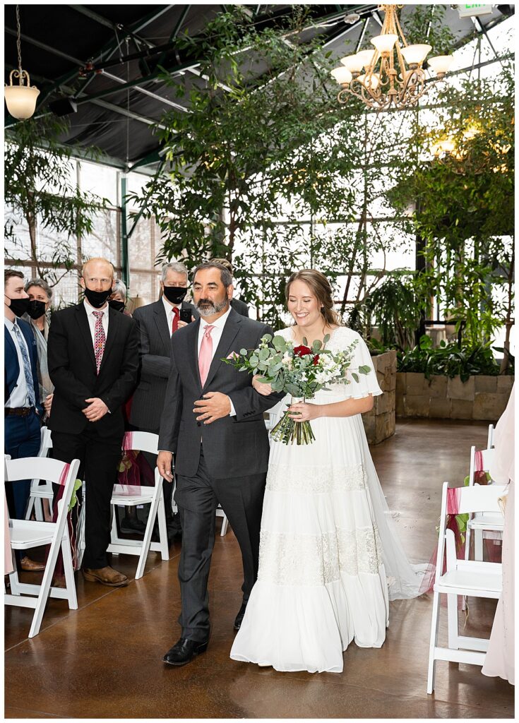 bride and father walking down the isle during indoor ceremony